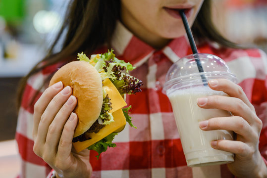 woman eat humburger and drink milk shake