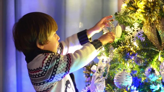 Cute little boy preparing for christmas, decorating christmas tree