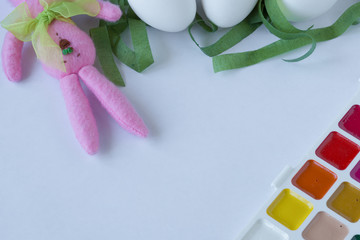 White eggs, Easter Bunny and watercolor paint on white background. Space for text