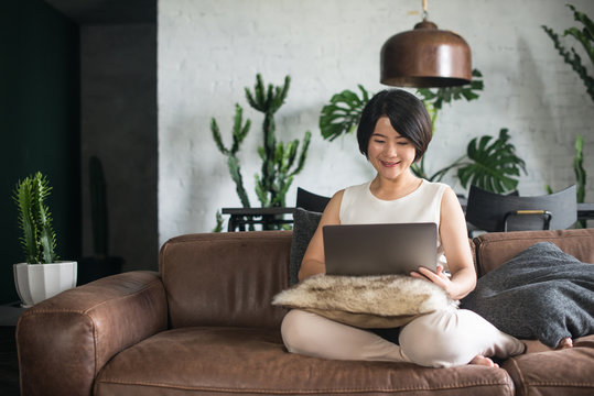 Happy Asian woman using the computer at home.