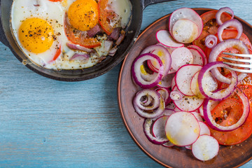 Fried eggs with vegetables, salad on a wooden background - top view, copy space, concept of rustic healthy food