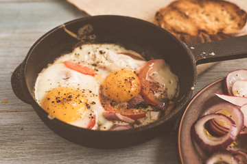 Fried eggs with vegetables, salad on a wooden background - top view, copy space, concept of rustic healthy food