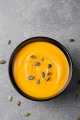Pumpkin cream soup, pumpkin seeds in a black bowl