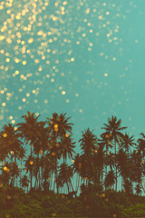 Fototapeta na wymiar Palm trees on tropical beach, vintage toned and retro color stylized with golden shiny glitter bokeh background