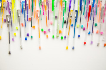 Bright, colorful pens on a white background shot overhead.