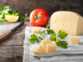 Piece of cheese with parsley, tomatoes on a linen towel Rustic wooden background