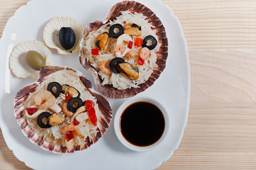 Rice in the shell, decorated with seafood, shrimps, mussels, squid rings and olives. Dietary food.