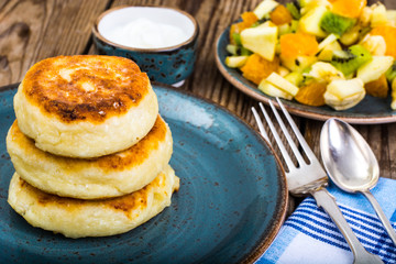 Hot delicious curd pancakes with fruit salad and yogurt