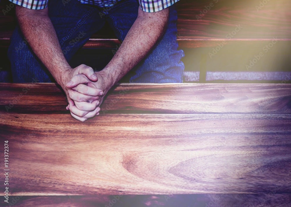 Wall mural man hands praying on wooden table with window light effected, christian background