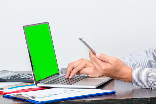 One businessman hold mobile phone while checking the data of  the sale volume report from laptop on white background