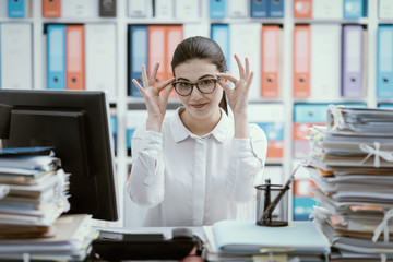 Confident secretary adjusting her glasses