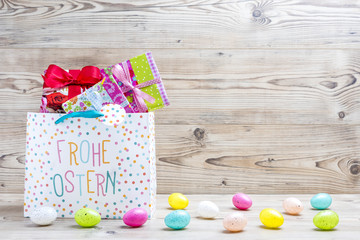 Obraz premium Ostergeschenke und Ostereier vor einem Holz Hintergrund