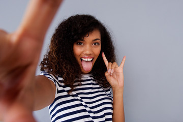 fun young african american woman taking selfie with tongue out