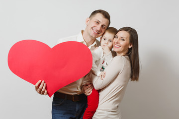 Joyful smiling young man, woman holding, hugging little cute child boy with big red heart isolated on white background. Father, mother, little kid son. Parenthood, family, parents and children concept
