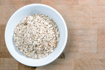 white bowl of oat flakes on wooden table