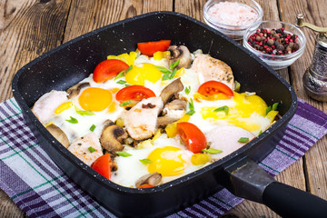 Fried eggs, tomatoes, ham, mushrooms in frying pan