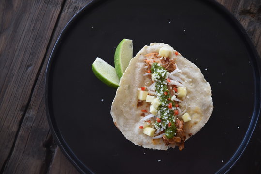 Filled tostada on black plate, elevated view