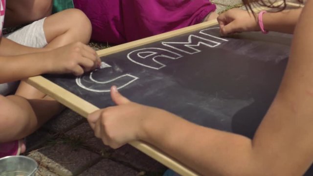 Young kids in summer camp writing on blackboard children playing outdoor in park slow motion