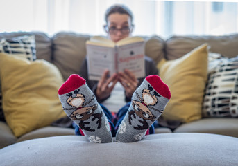 Girl in warm socks reading a book. Selective focus
