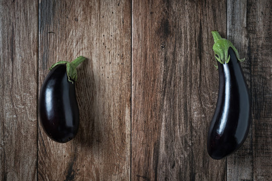 Pair of Shiny Eggplants on rustic wooden bacground. Copy space.