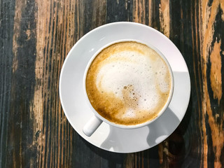 Cappuccino in white cup on old wooden table