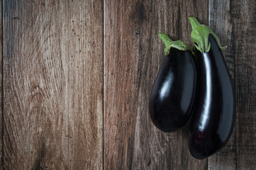 Pair of Shiny Eggplants on rustic wooden bacground. Copy space.