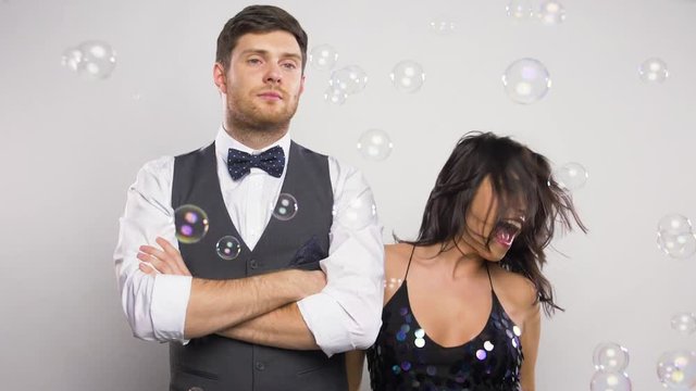 happy woman and bored man at party with bubbles