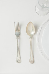 White Vintage Empty Plates Half Circle Silver Fork Spoon Wine Glass on Concrete Tabletop. Minimalist Japanese Style Table Setting. Template for Poster Banner Cooking Workshop Course. Easter Christmas