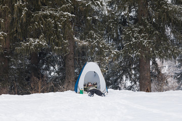man in a tent in a winter forest © serikbaib