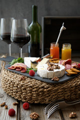 Red wine and a variety of snacks. Rustic wooden table and dark gray background
