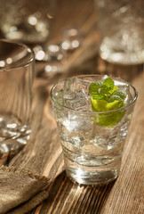 Glass of gin tonic with lime and ice over a wooden table