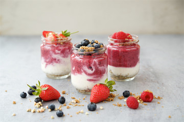 Berry breakfast on light background. Strawberries, blueberries, raspberries, yogurt, green buckwheat and nut paste ingredients
