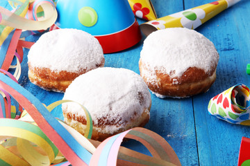 German donuts with jam and icing sugar. Carnival powdered sugar raised donuts with paper streamers.