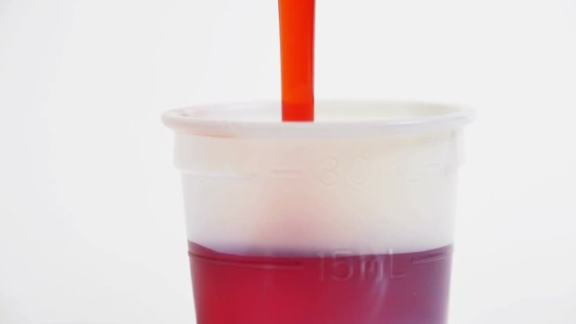 Red Cold Medicine Pouring into Cup Isolated on White Slow Motion