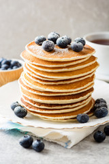 Pancakes with blueberries and sugar on grey stone background.