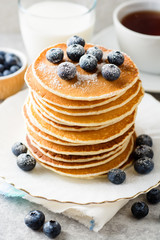 Pancakes with blueberries and sugar on grey stone background.