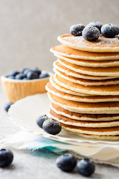 Pancakes with blueberries and sugar on grey stone background.