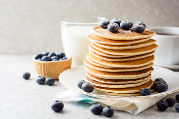 Pancakes with blueberries and sugar on grey stone background.