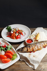 grilled mackerel and a salad of fresh vegetables. Serving on a wooden Board on a rustic table. Barbecue restaurant menu, a series of photos of different meats anf fish