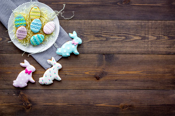 Easter bunny and easter eggs cookies. Sweets, pastry for Easter table. Dark wooden background top view copy space