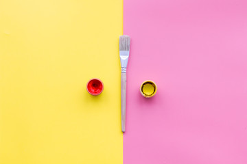 Empty steel fork on yellow and pink background top view copy space