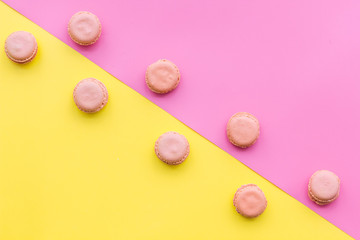 Macarons dessert. Pattern on yellow and pink pastel background top view copy space
