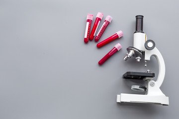 Do blood test in laboratory. Analysis. Blood samples in test tubes near microscope on grey background top view copy space