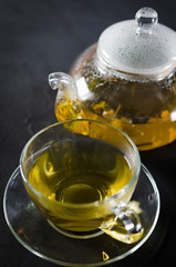 Cup of delicious herbal tea and glass teapot.