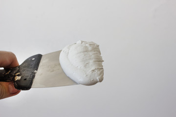 Spatula with putty on white background