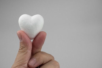 Gray background and Little white heart on hand , Pure love symbol
