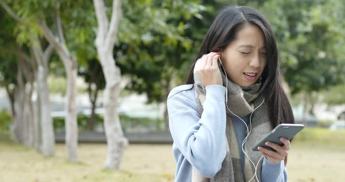 Woman listen to music on cellphone by earphone
