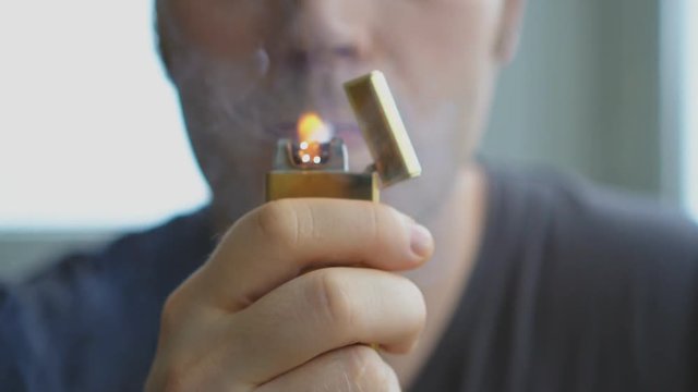 Man lights a cigarette with electronic cigarette lighter.