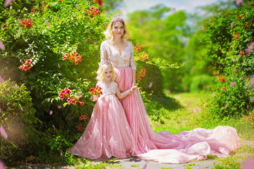 Obraz na płótnie Canvas Beautiful mother and daughter in pink dress on background of summer park. Lovely Princesses