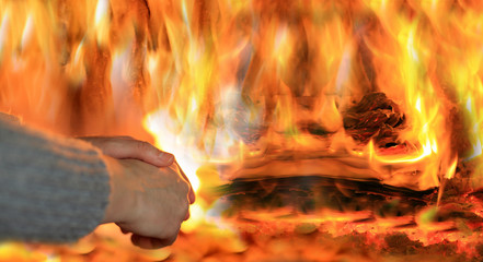 Ogień w kominku, kobieta grzeje dłonie. - obrazy, fototapety, plakaty
